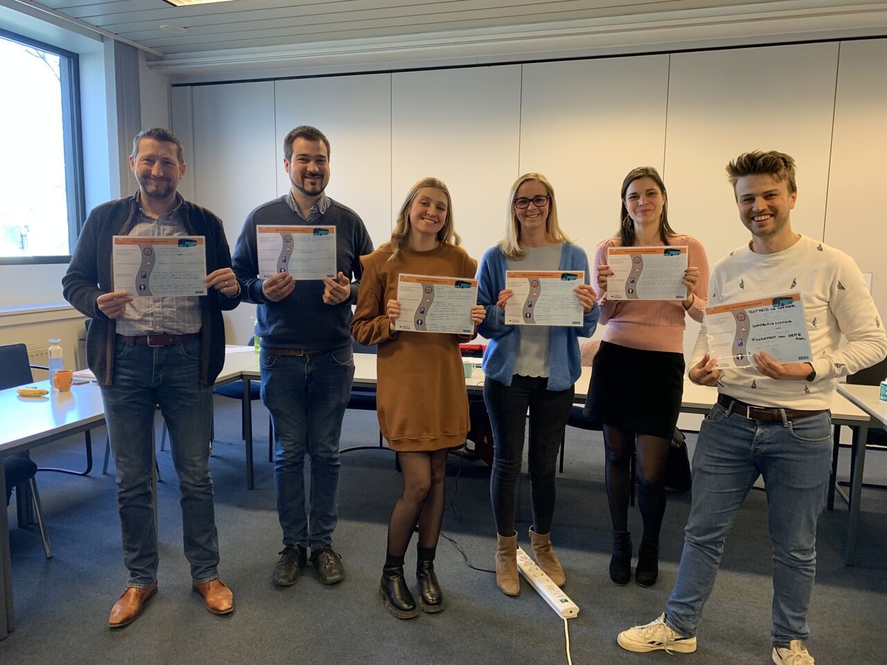 Zes deelnemers tonen hun certificaat na een opleiding