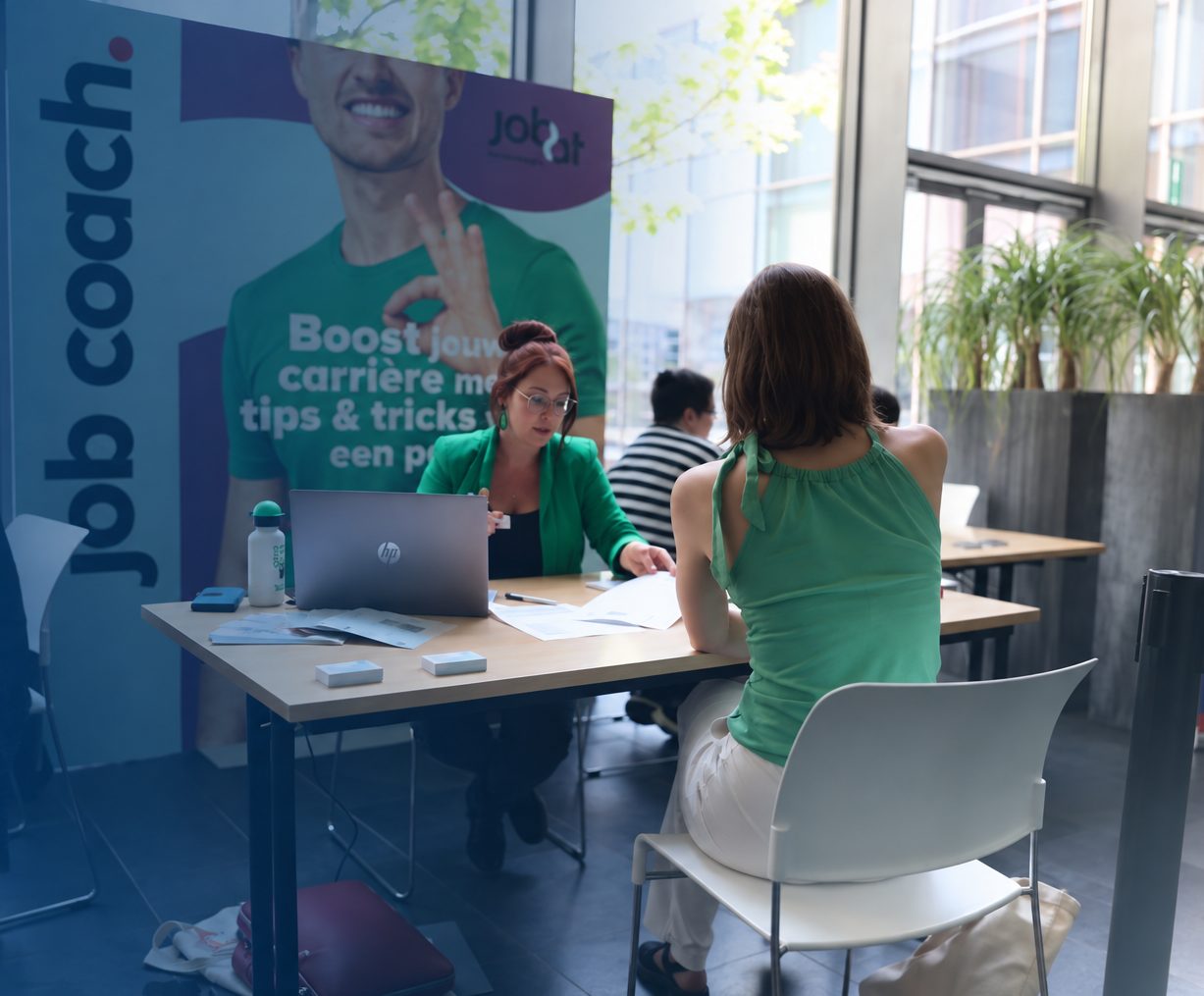 Katrijn aan tafel met een deelneemster, op een jobbeurs