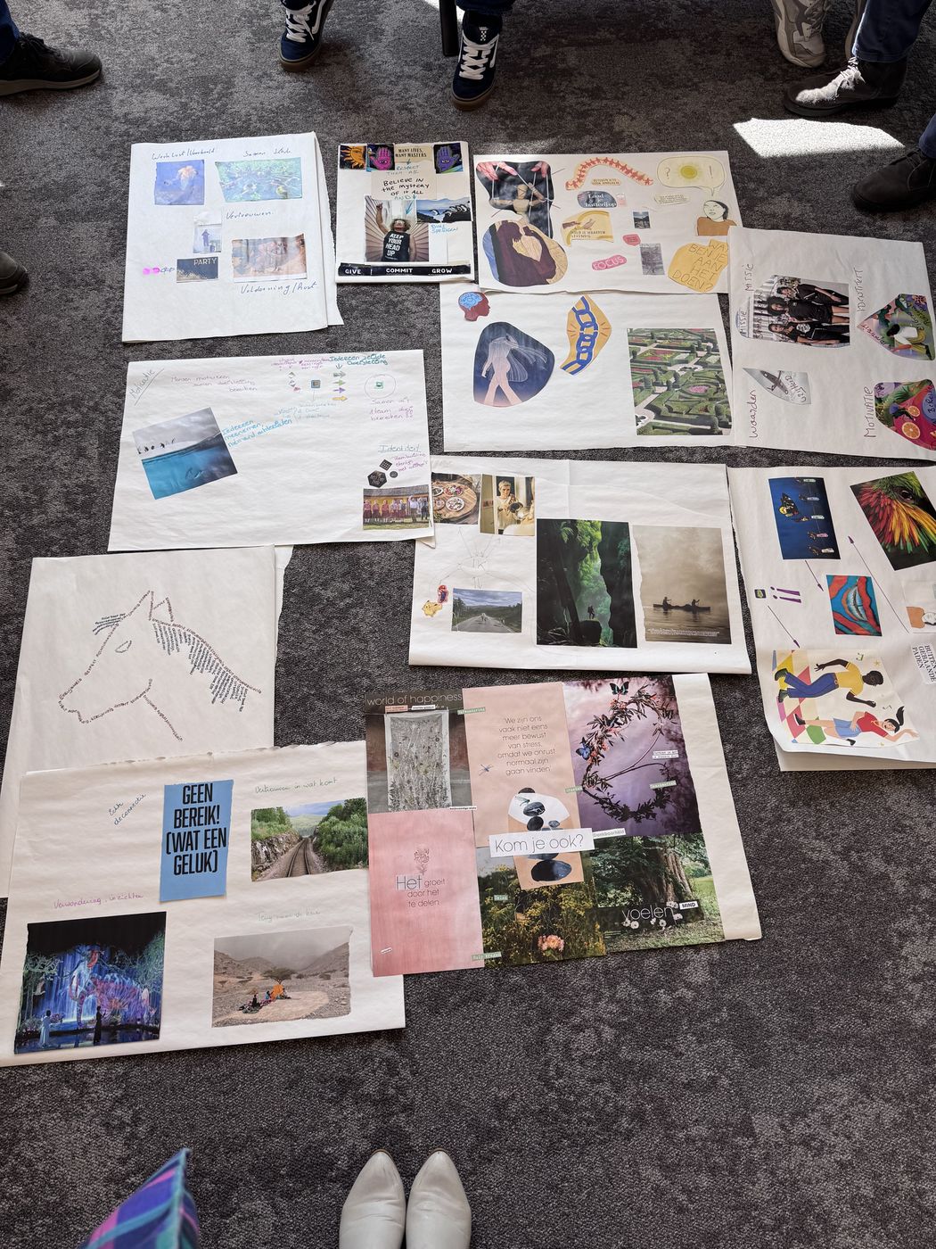 Collages met foto's en tekeningen op de vloer van een opleidingszaal