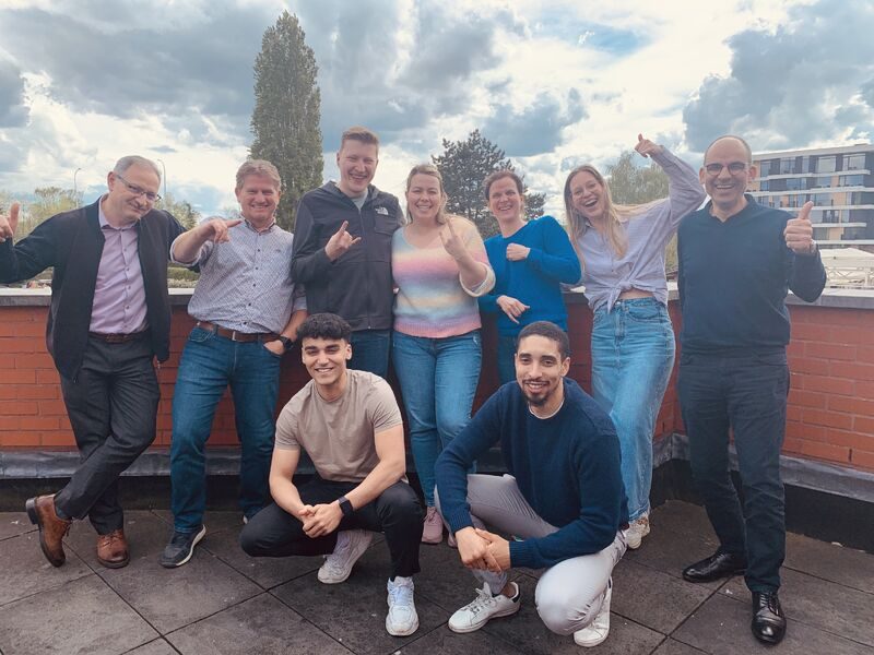 Een groep deelnemers poseert lachend buiten op een terras
