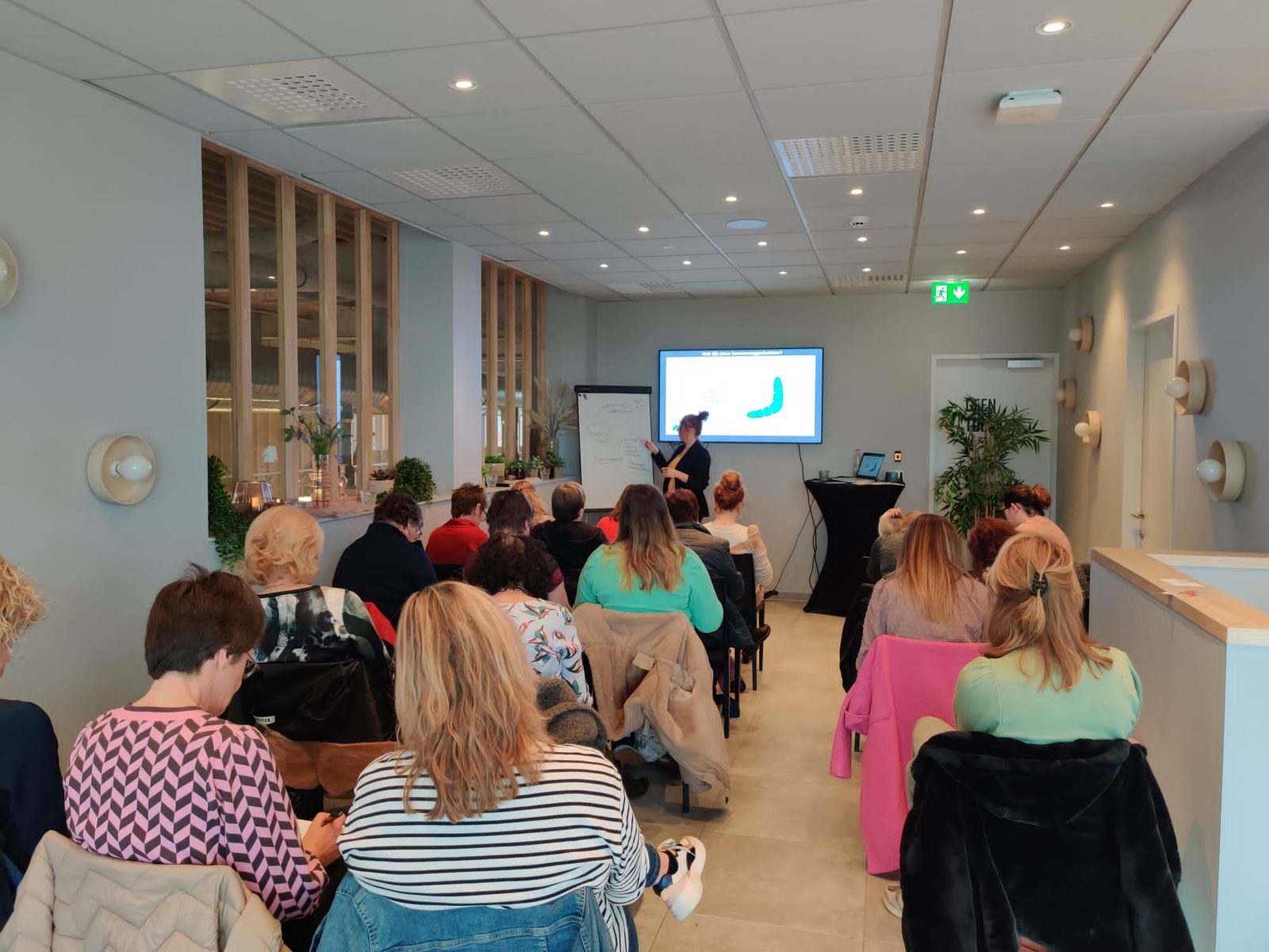Een volle zaal deelnemers kijkt naar een presentatie